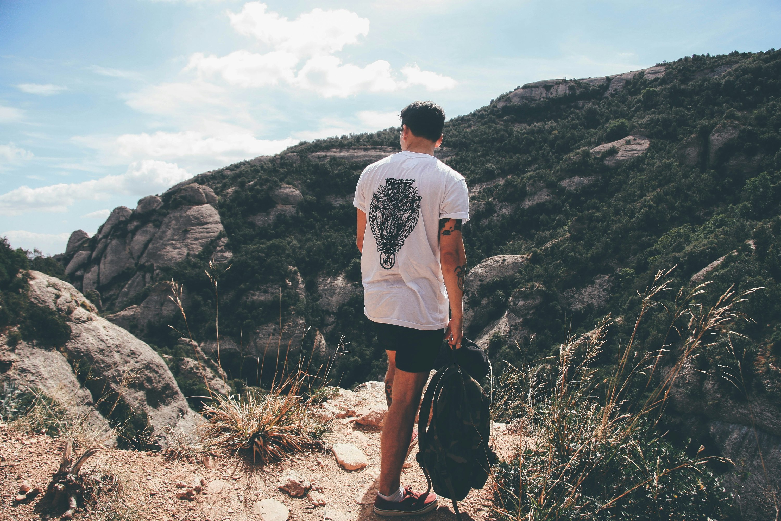 man holding backpack standing near pathway